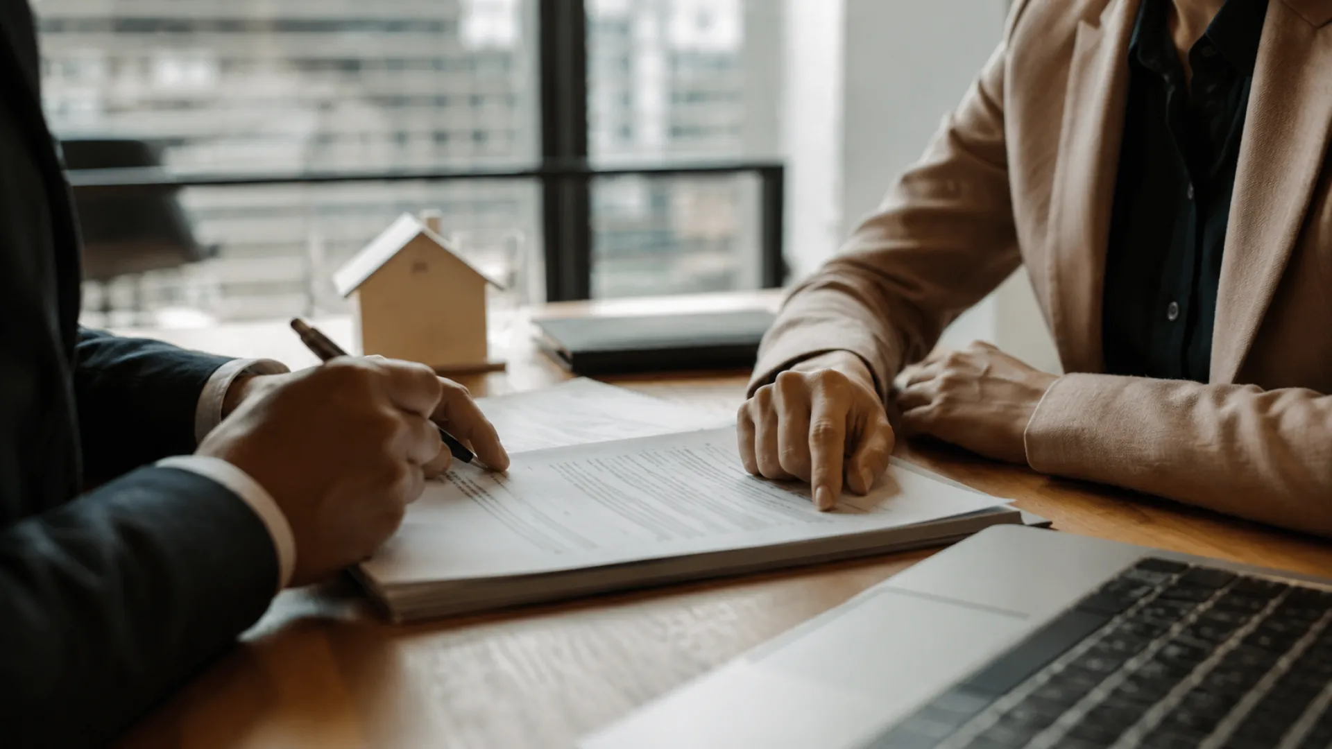Comprador y vendedor revisan documentos junto a abogado durante venta de vivienda hipotecada.